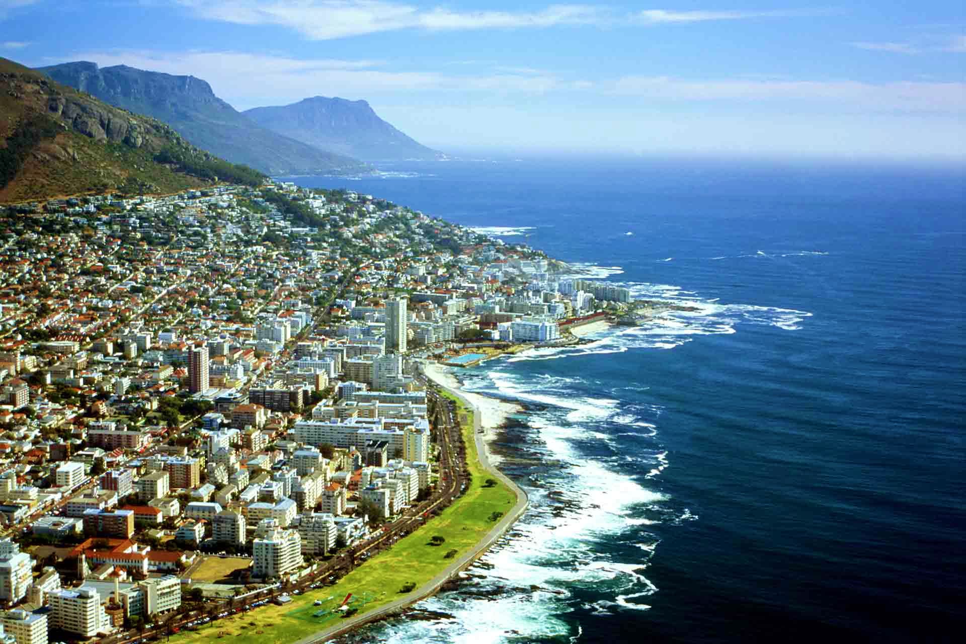South Africa Visa Aerial view of Cape Town coastline with Table Mountain, urban development, and Atlantic Ocean waves
